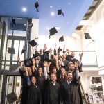 Absolventen werfen ihre Hüte bei der Absolventenfeier der Business School Kempten